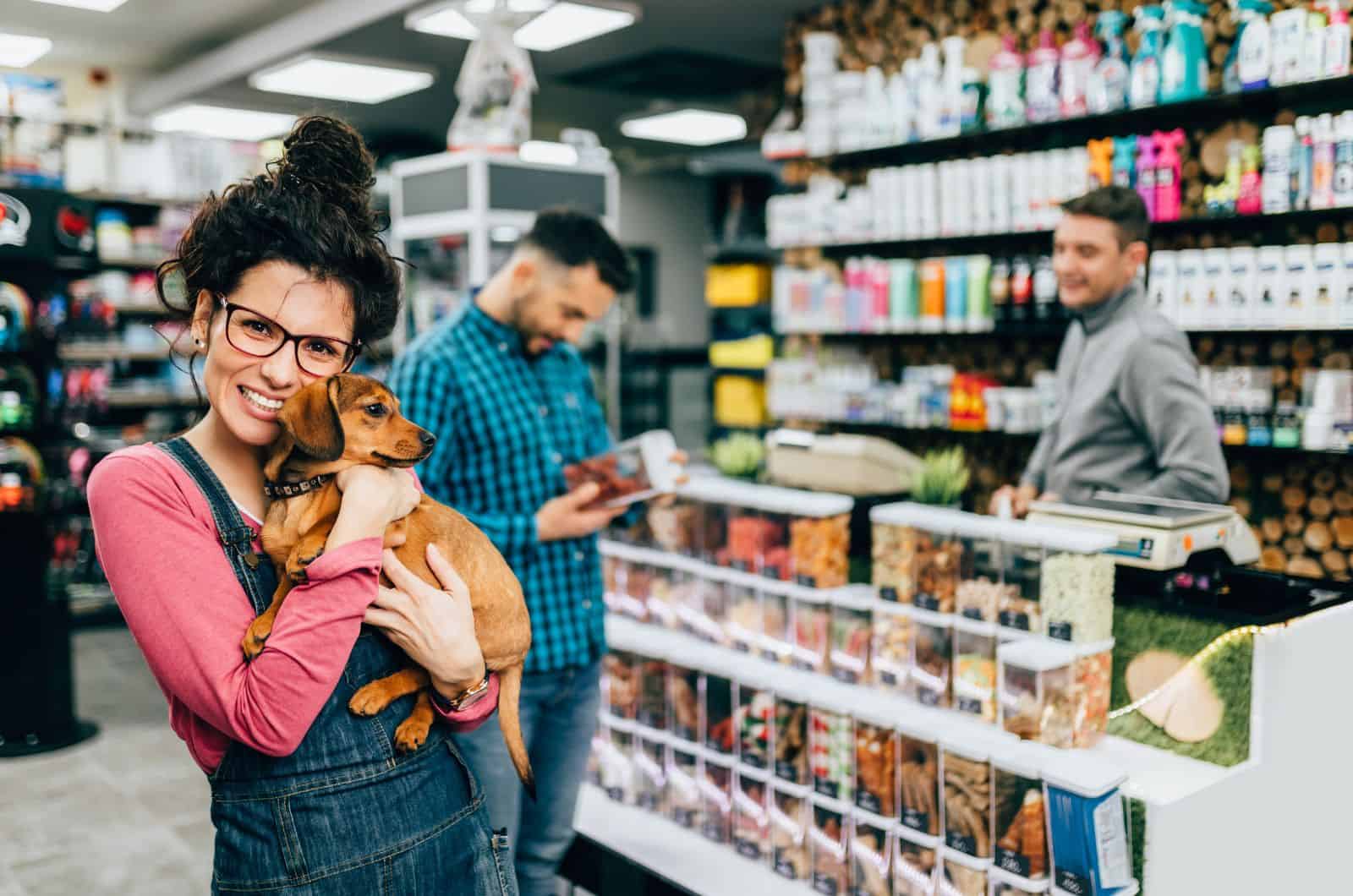 happy woman holding her dog in store