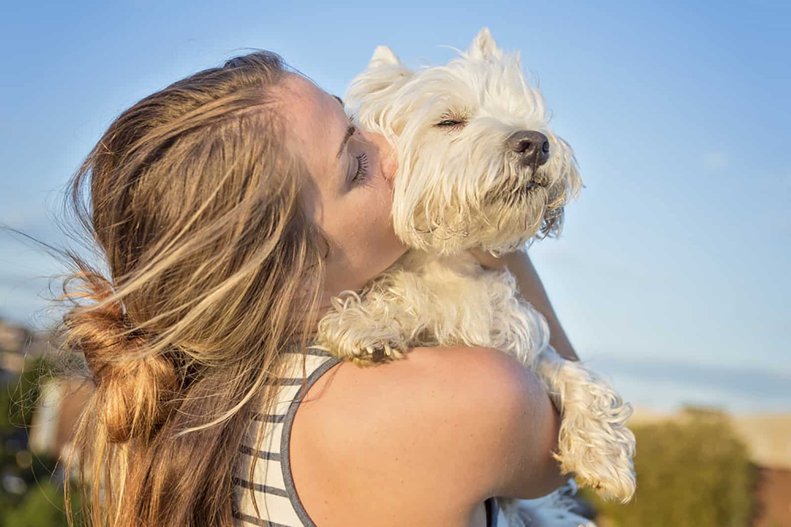 woman hugging west highland white terrier in nature
