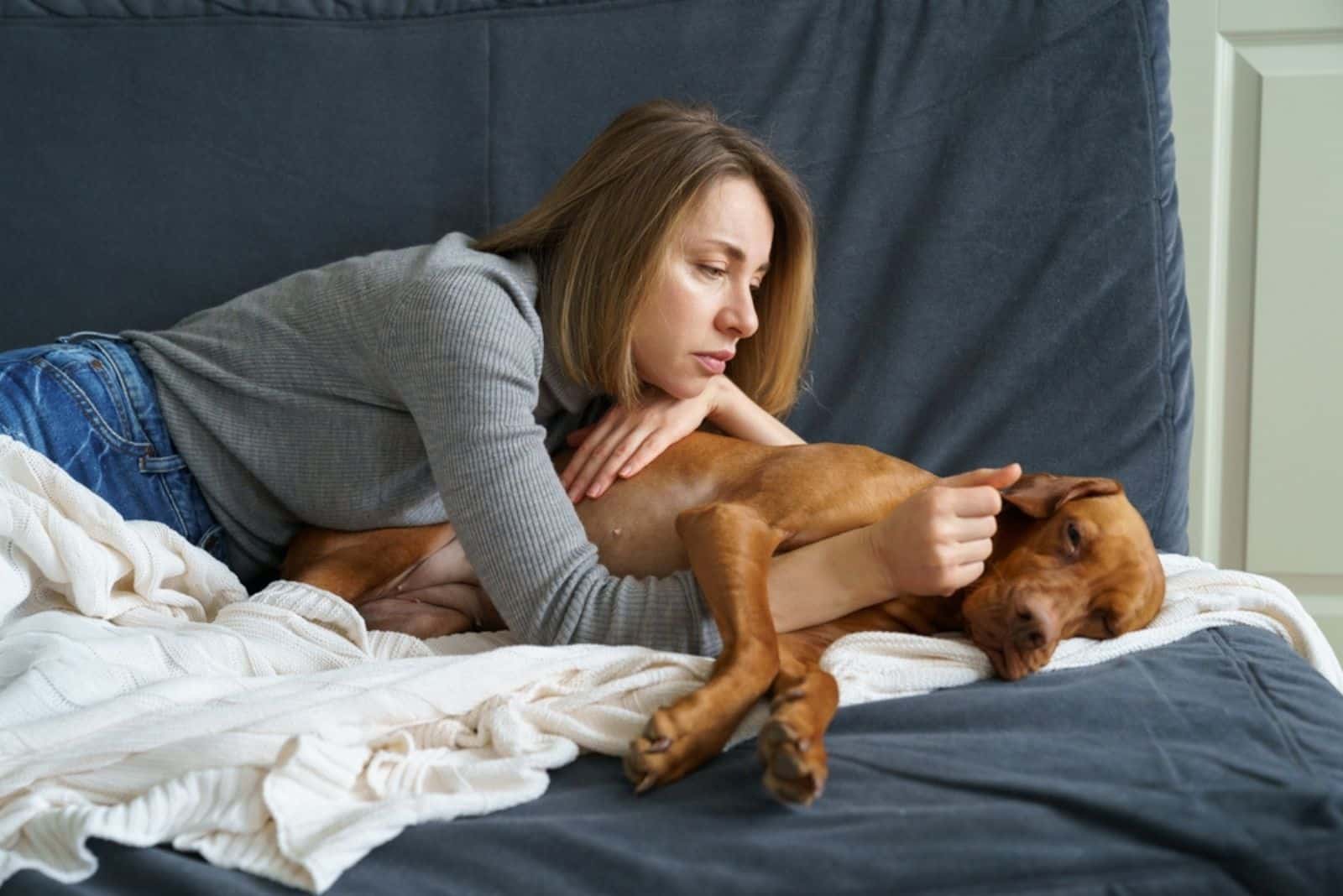 Worried woman taking care of weakening old dog 