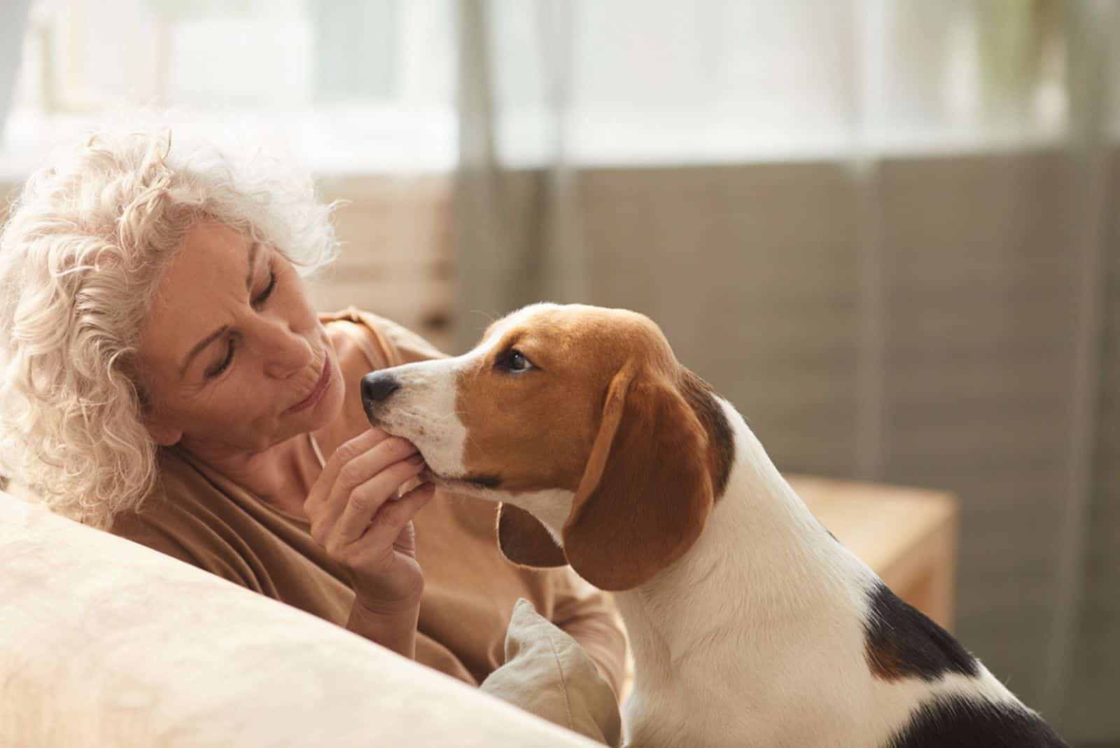 senior woman playing with dog and giving him treats