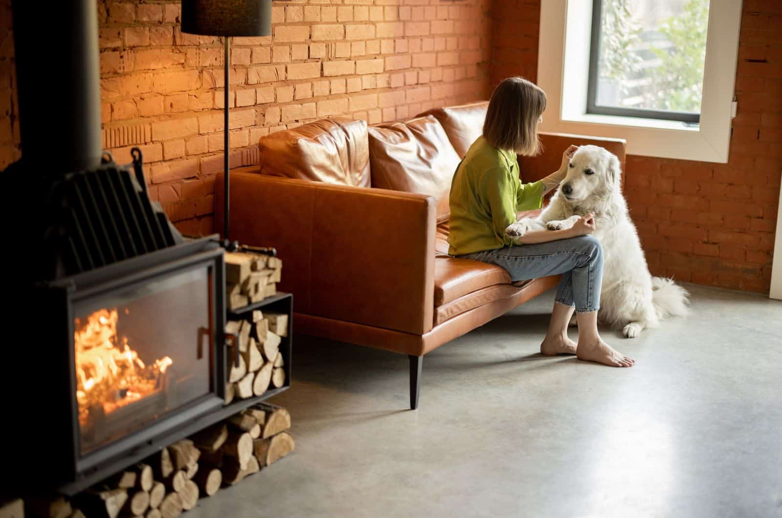 woman sitting on sofa petting her dog