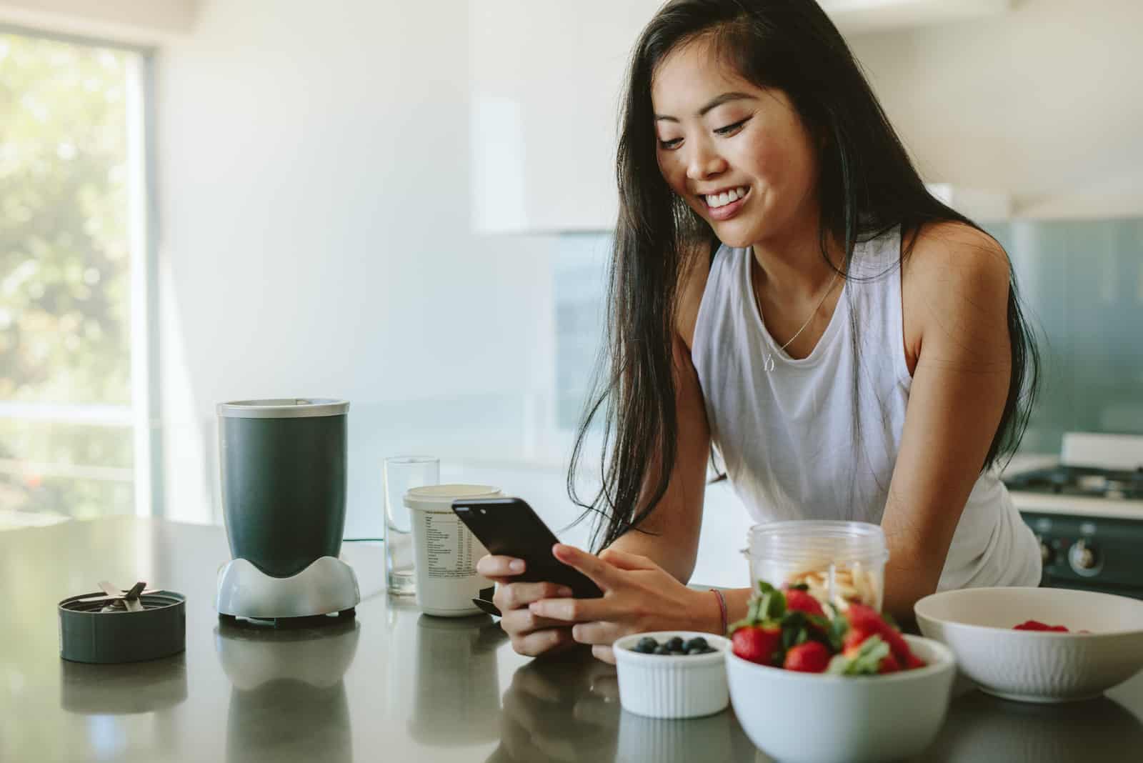 woman texting while standing in kitchen