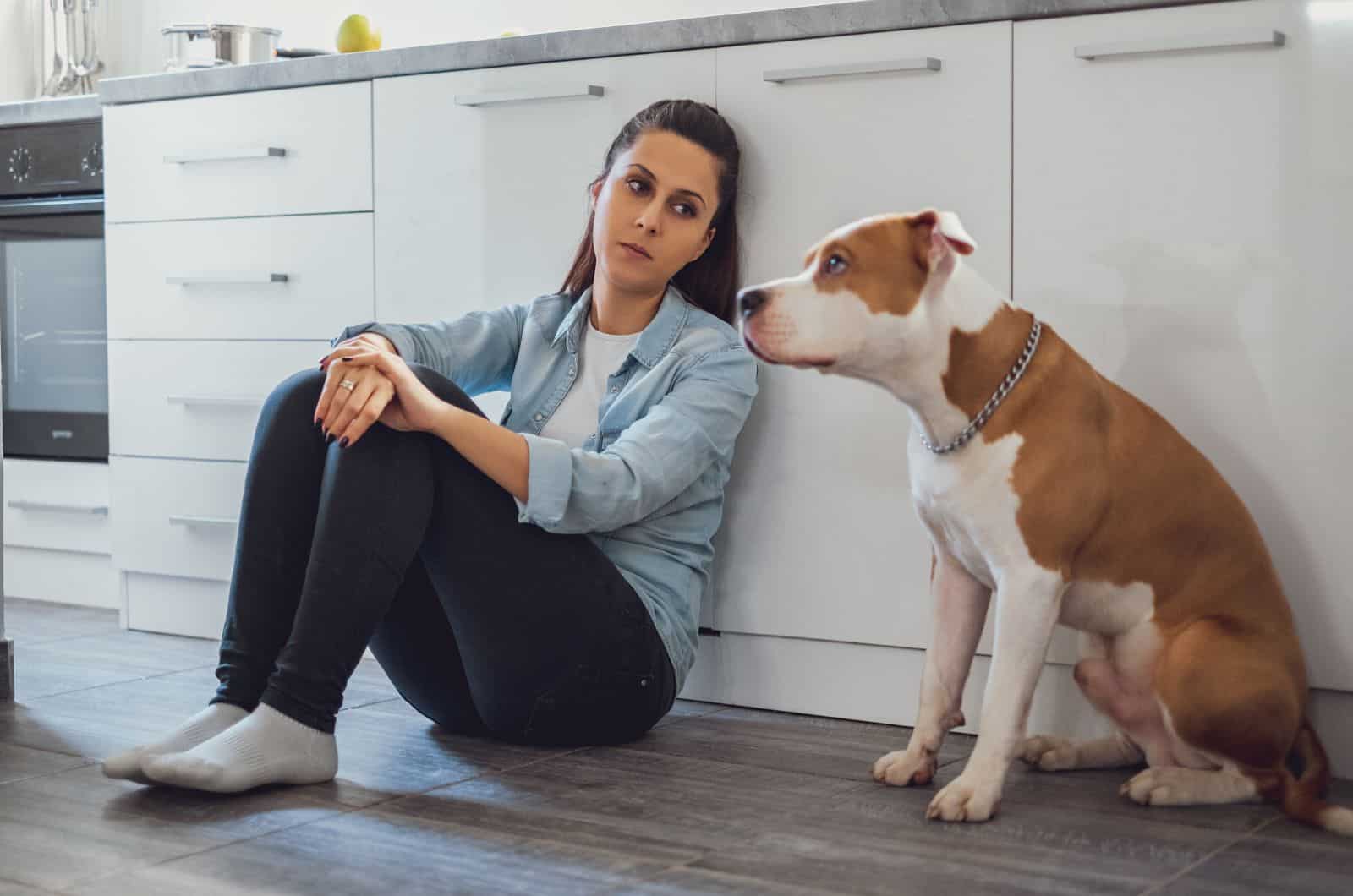 girl and dog sitting on kitchen floor