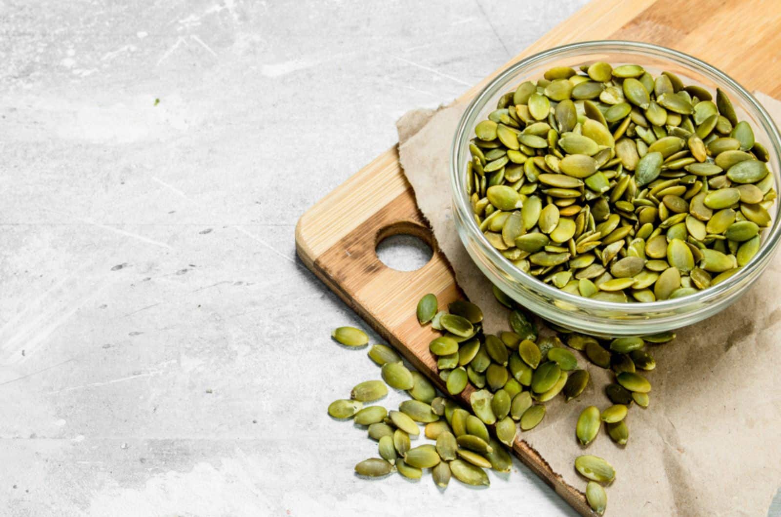 pumpkin seeds in a bowl on the kitchen board