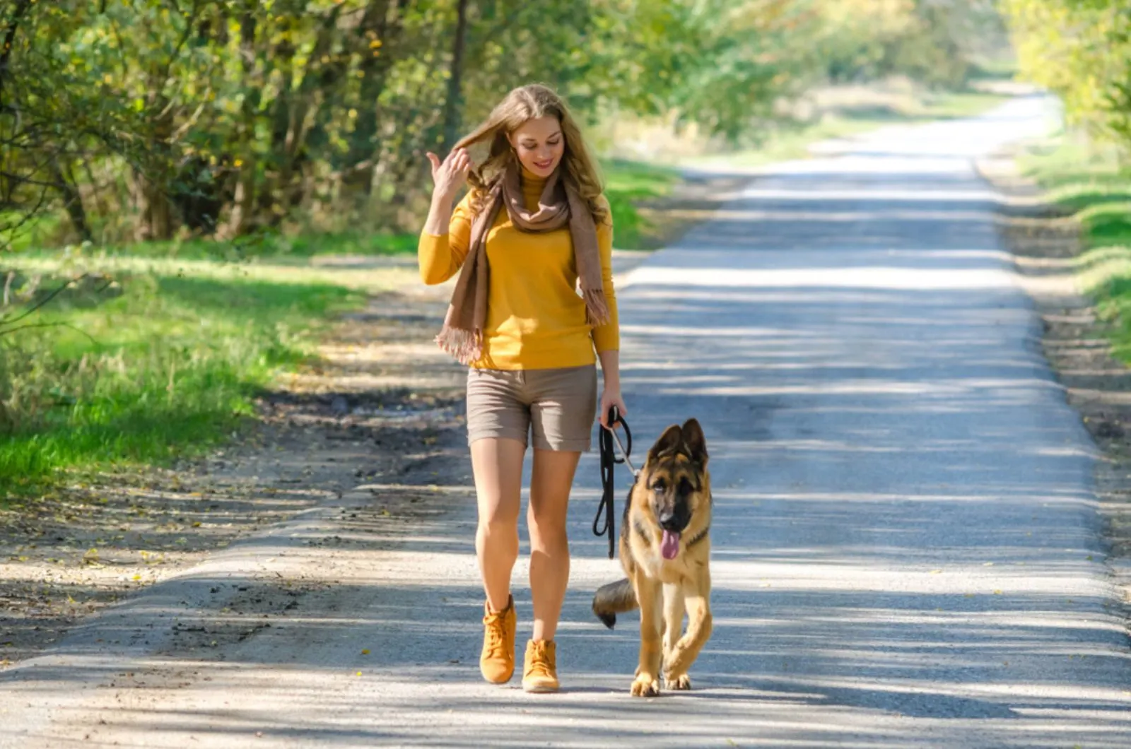 a girl walking with her dog german shepherd on the road