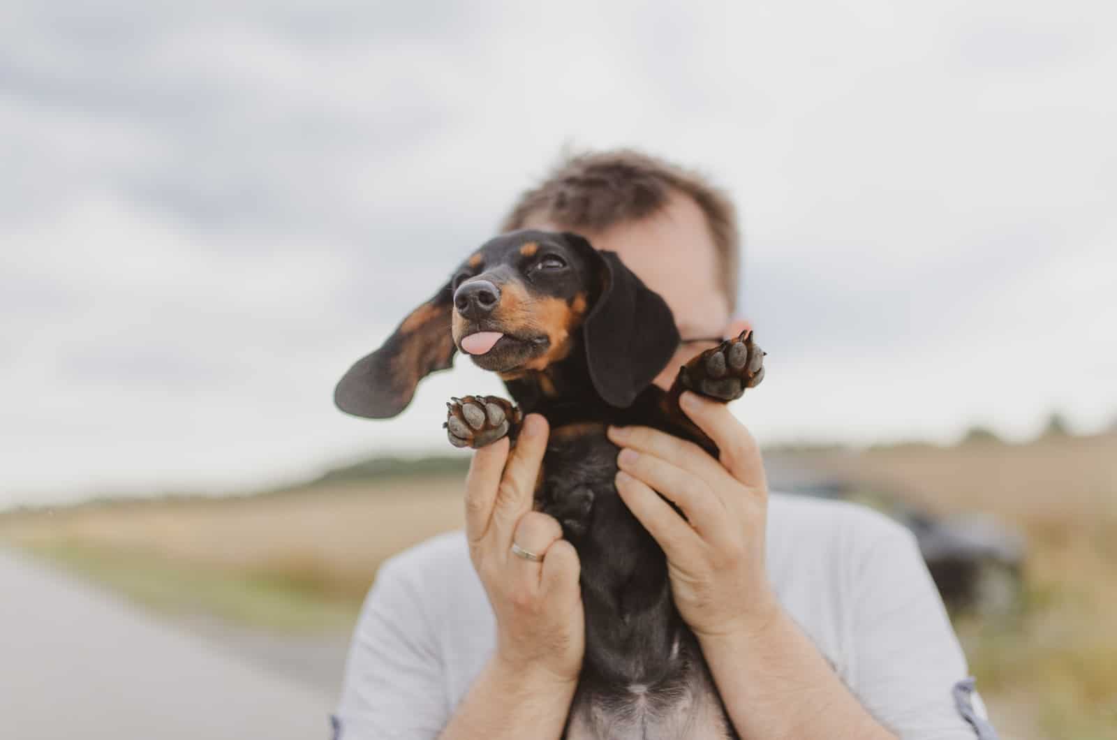man holding his dachshund puppy