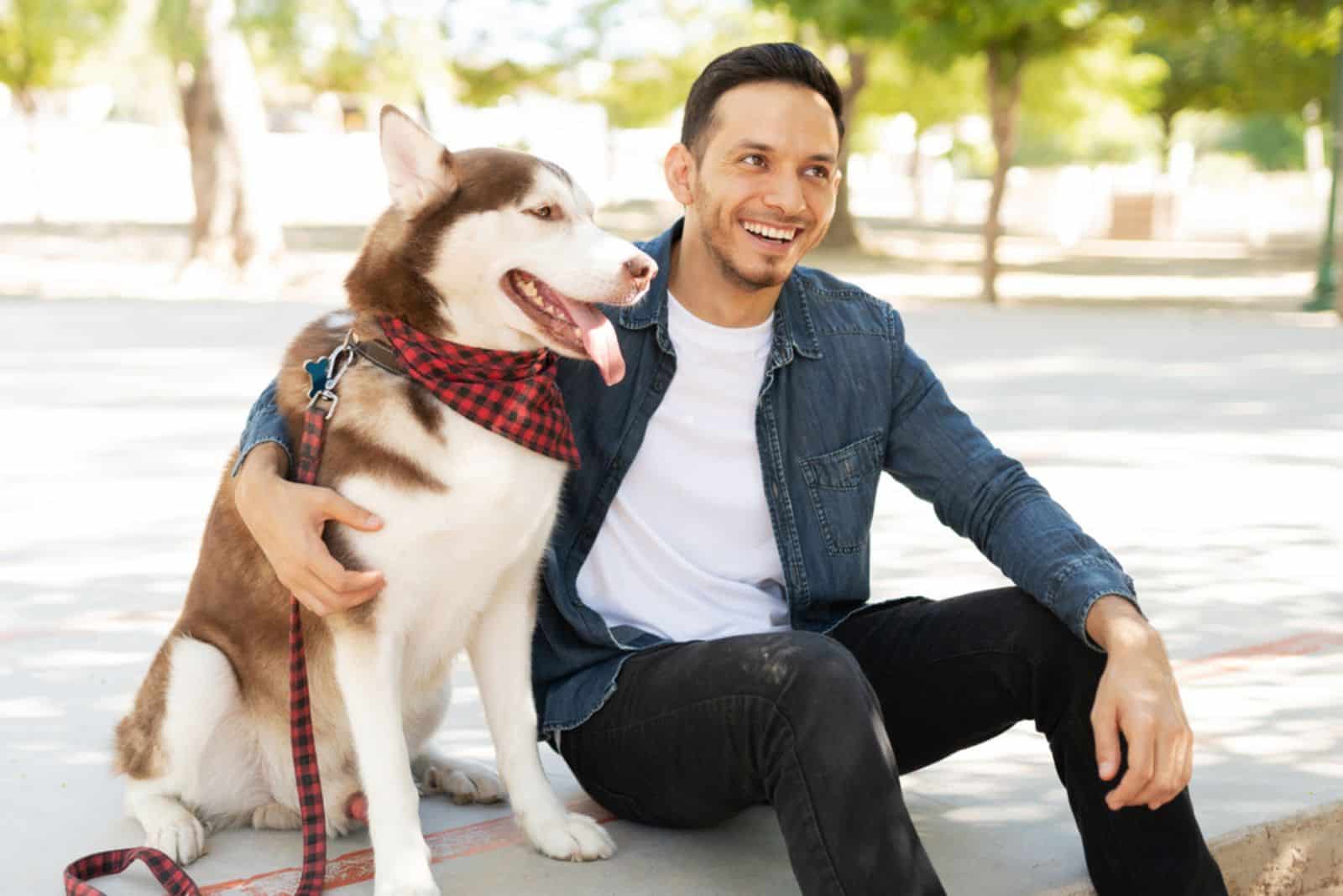 Attractive male dog owner laughing and embracing a beautiful husky 