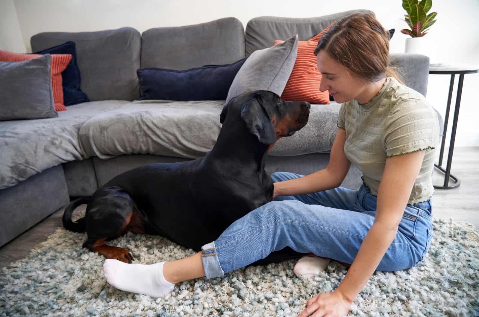 Doberman playing with girl on floor