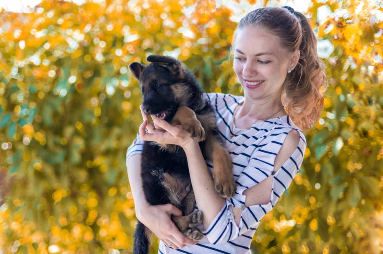 a girl holding a german shepherd puppy and smiling