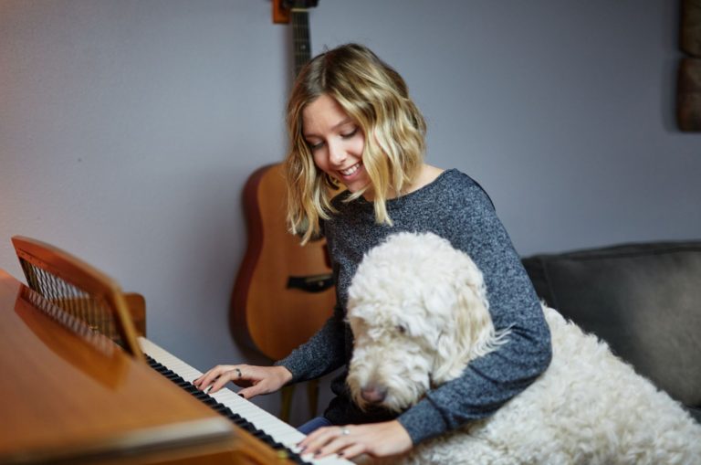 woman playing piano with goldendoodle