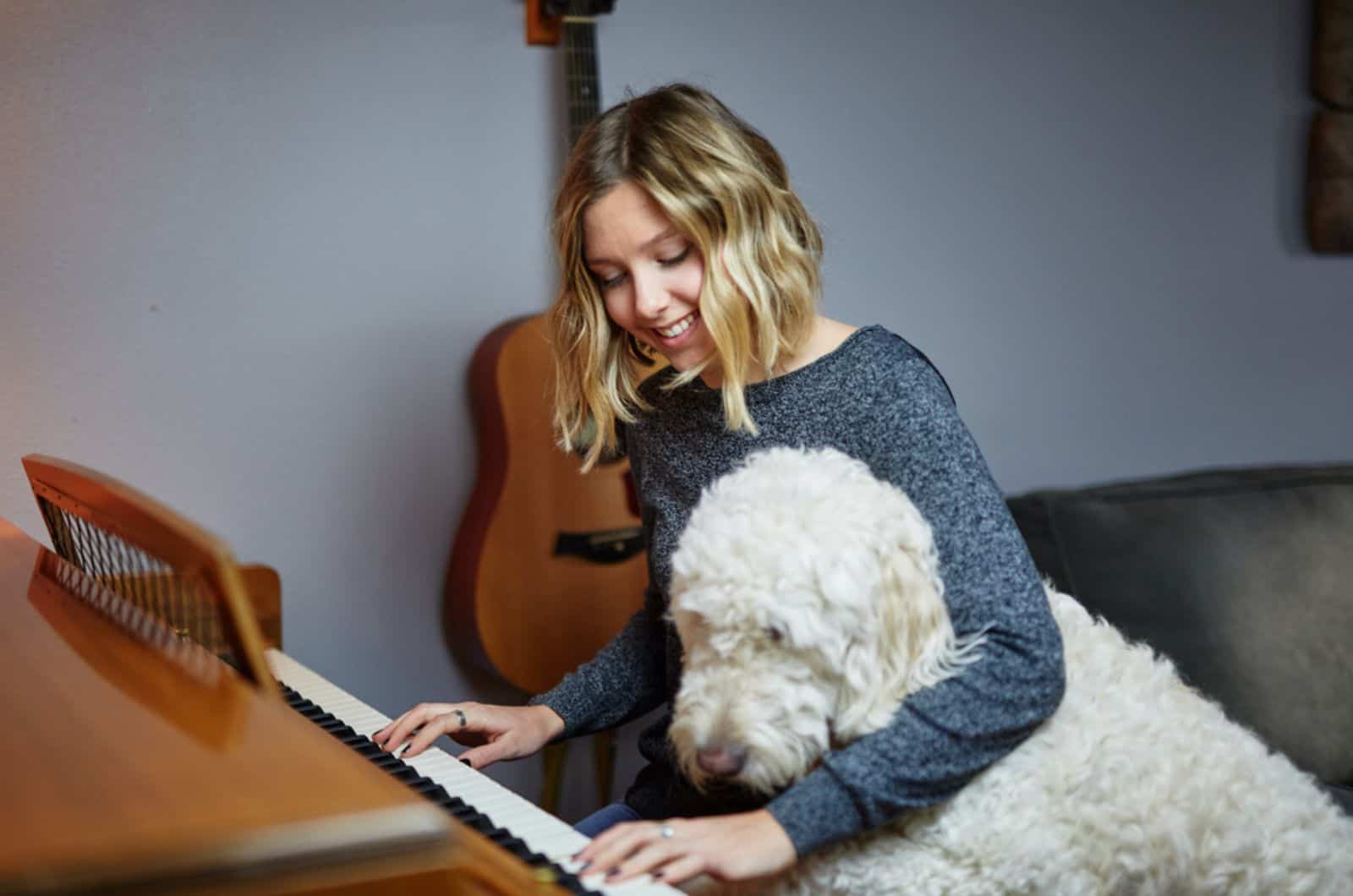 woman playing piano with goldendoodle