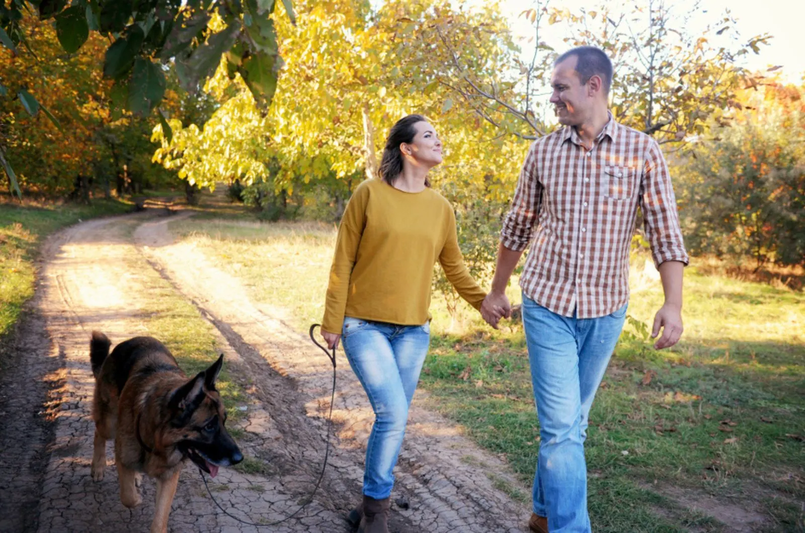 couple walking with german shepherd dog in the park