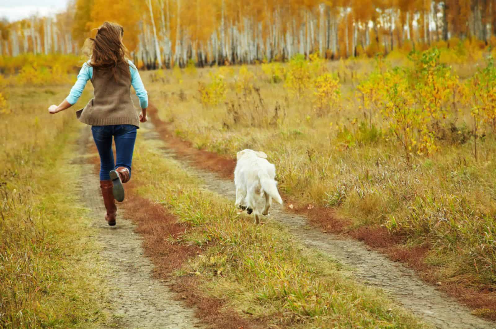 dog running away from a woman in nature