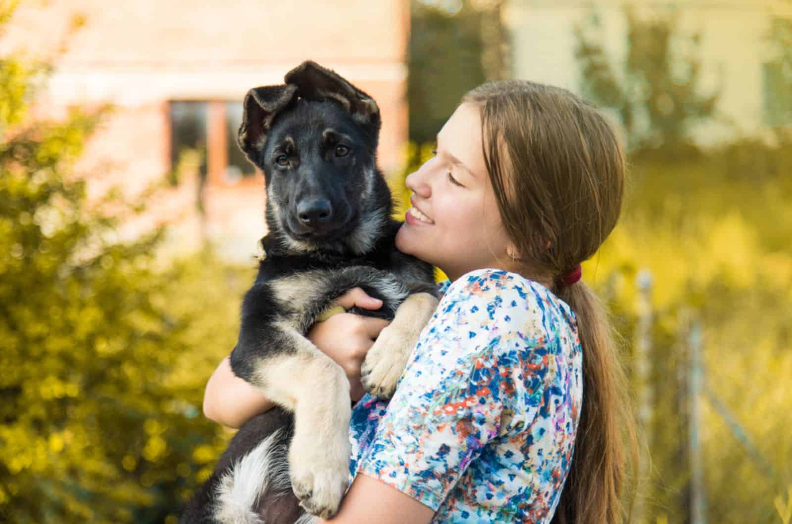happy girl holding german shepherd puppy in her arms