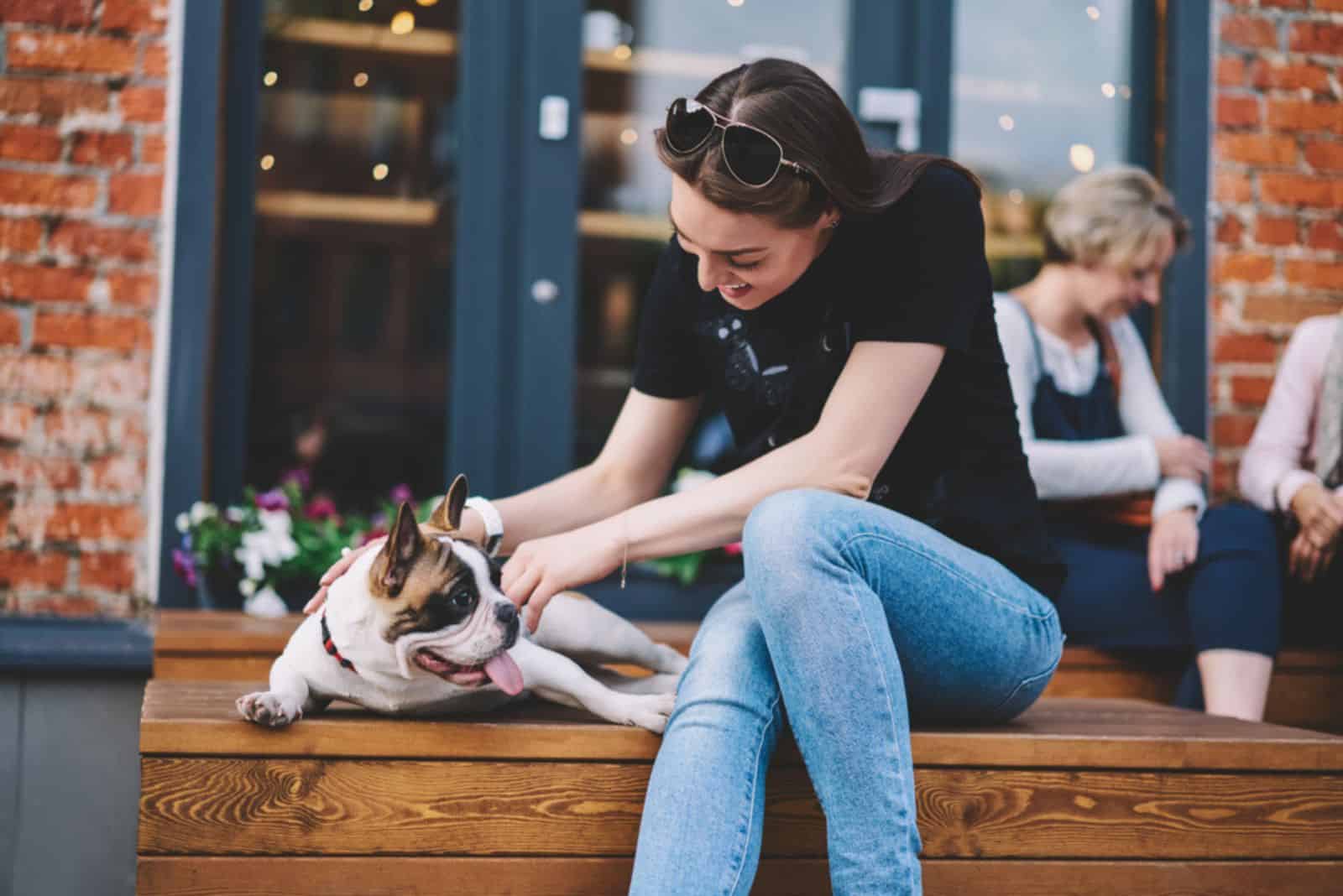 the puppy dog is excited while the woman is petting him on the bench