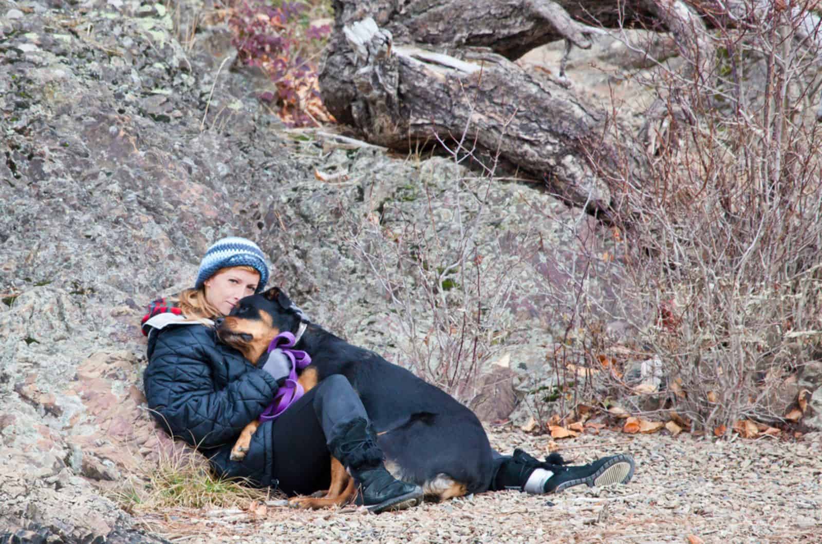woman and her dog hugging in nature