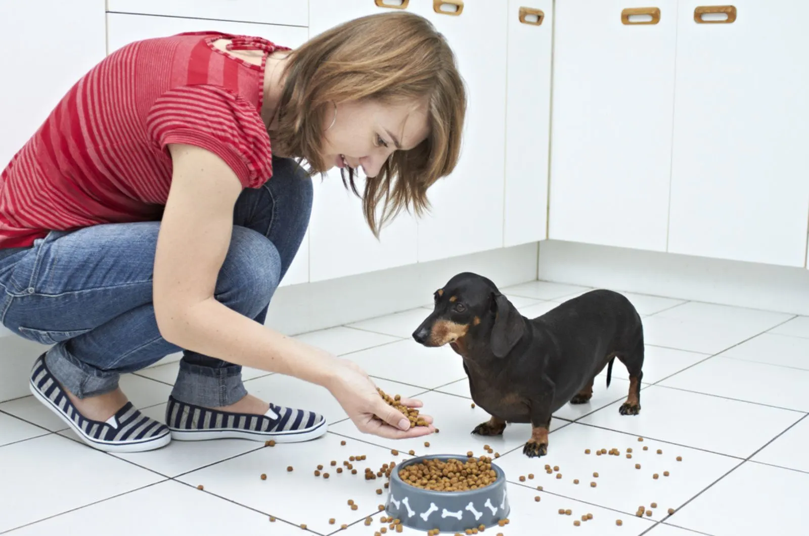 woman feeding her dog in the kitchen