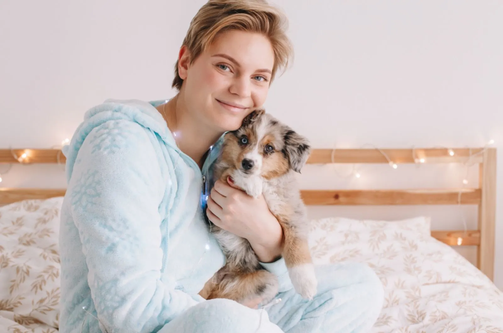 woman holding her puppy on the bed