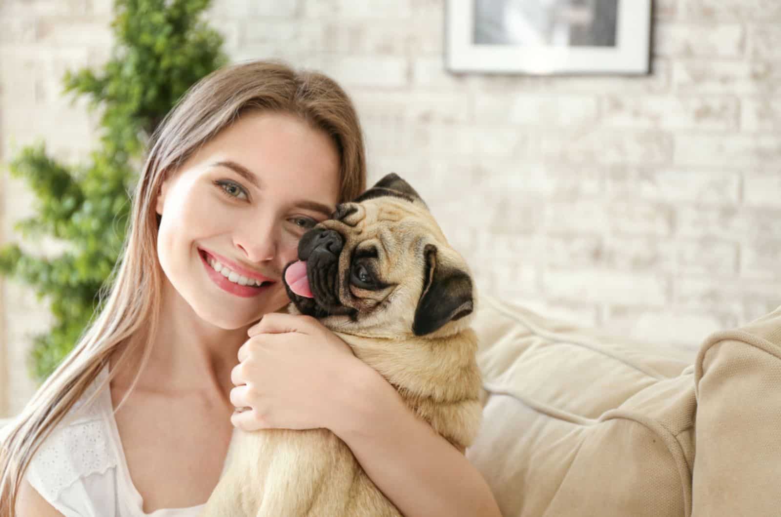 woman hugging her pug at home