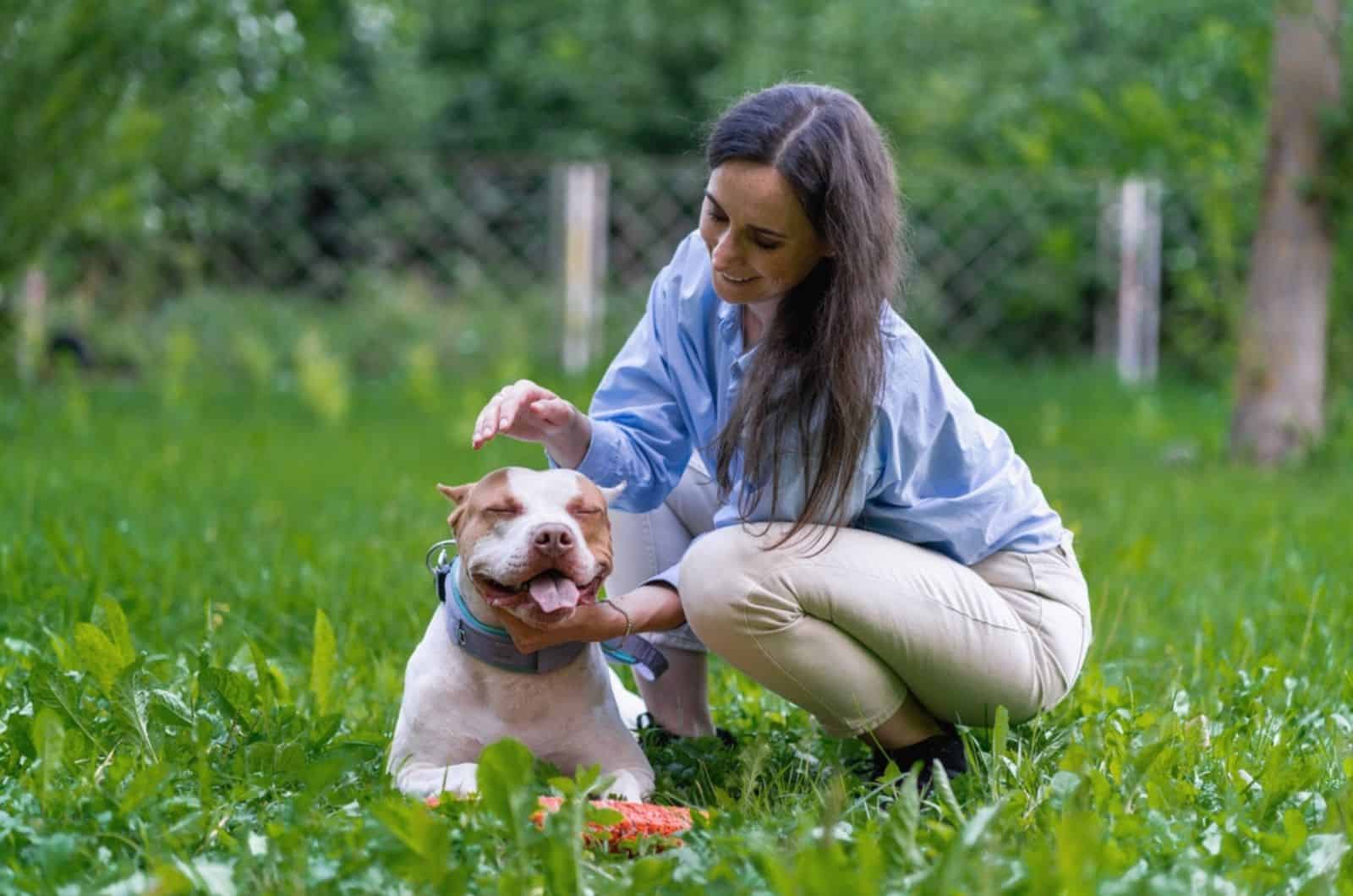 woman petting pitbull in the garden