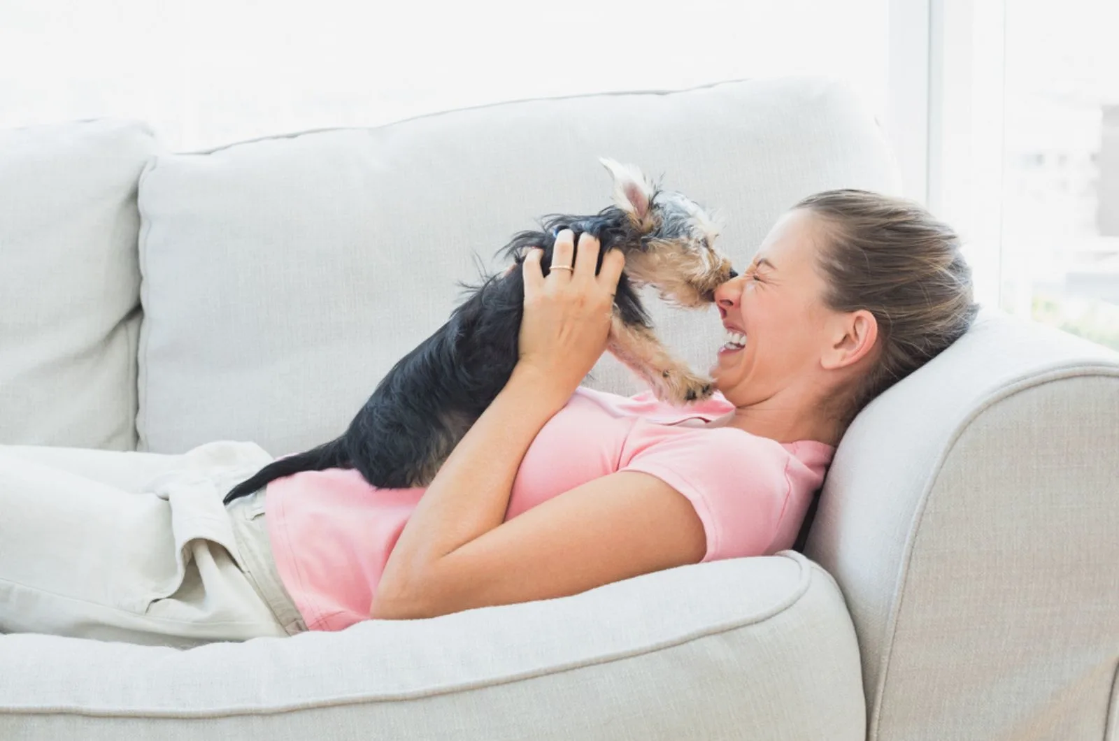 woman playing with her yorkshire terrier on the couch