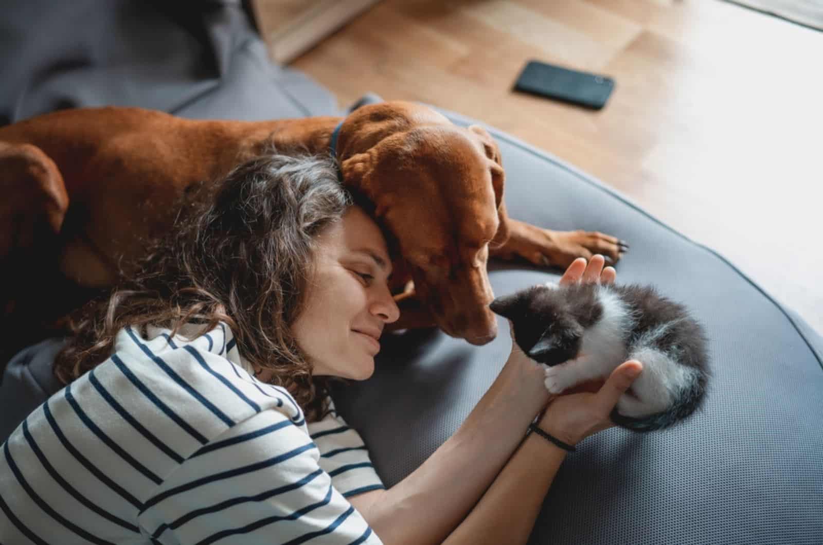 woman with a dog and a small kitten lying at home