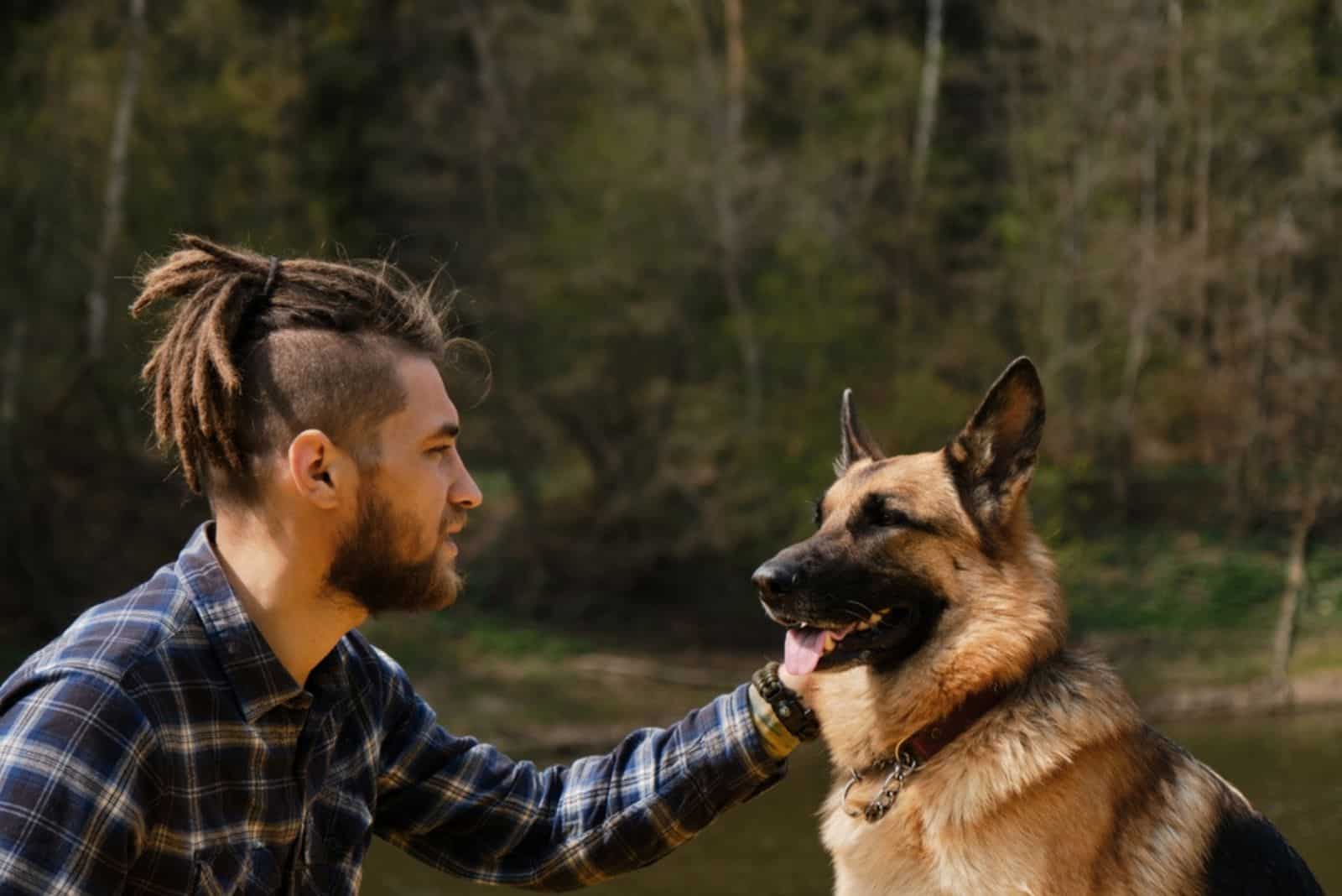 young man petting his german shepherd outdoor