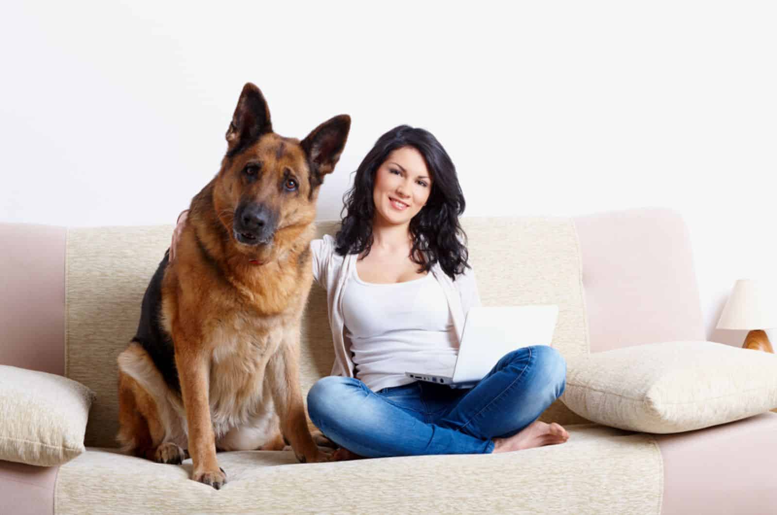 young woman sitting with her german shepherd on the sofa
