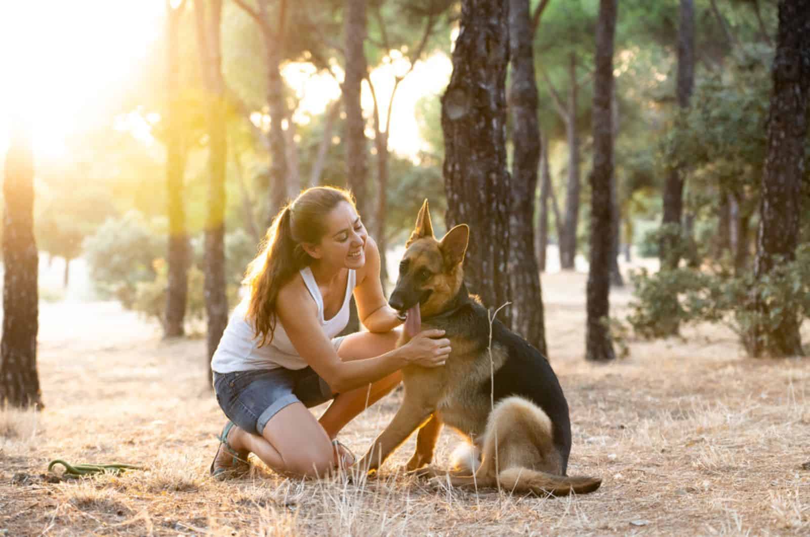 woman having fun with her german shepherd dog in nature