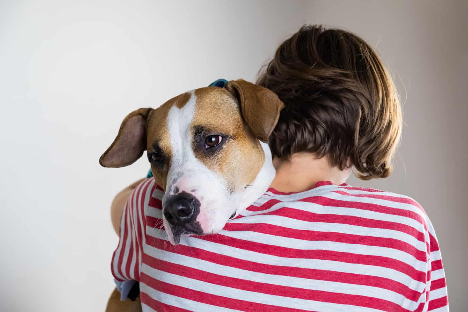 Woman hugs her dog in studio background