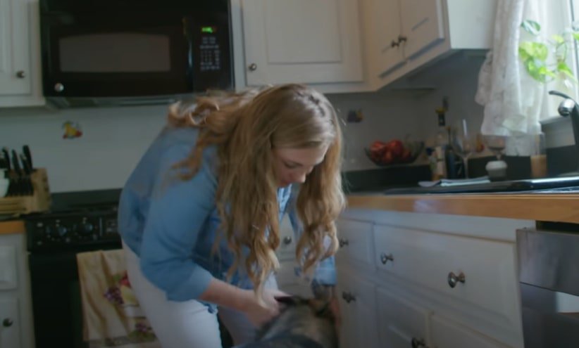 a German shepherd helps a woman in the kitchen