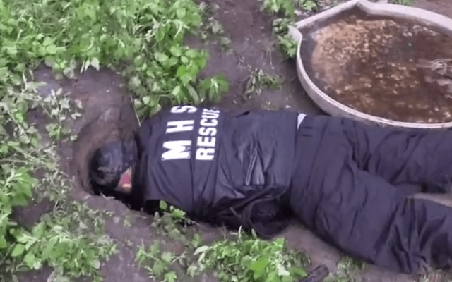 a man rescues a dog from a hole