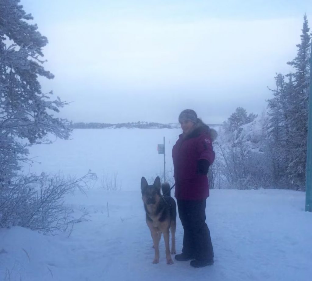 woman and dog standing outside in the snow