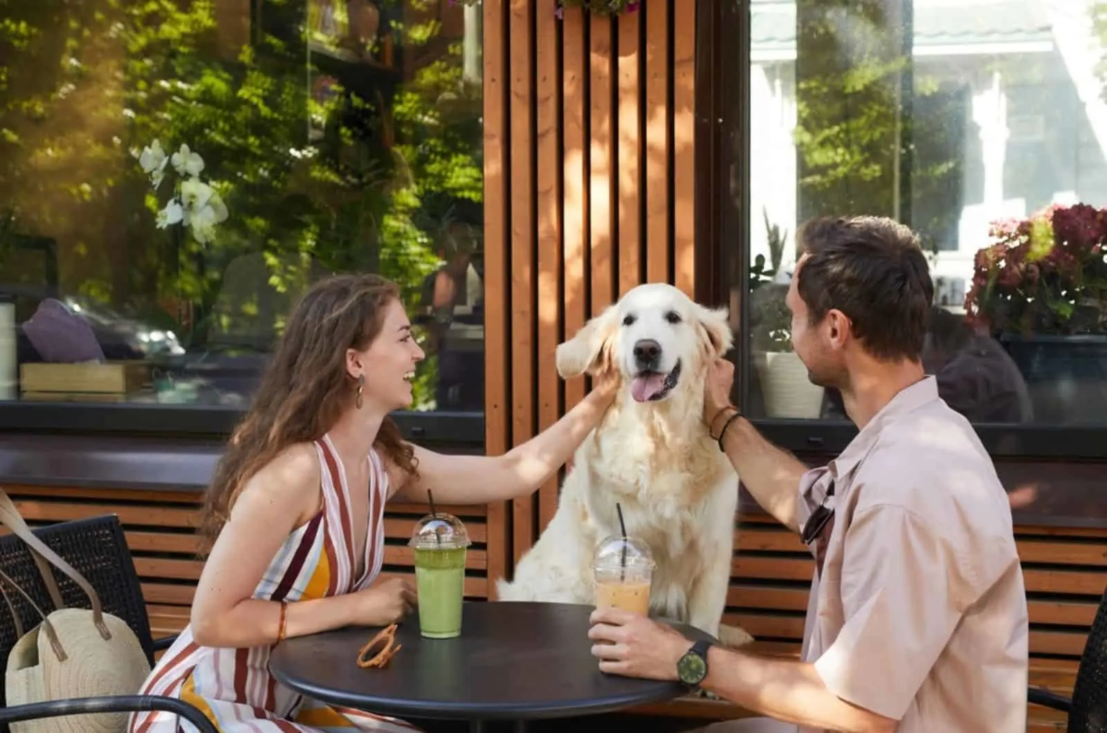 man and woman cuddling dog in outdoor cafe
