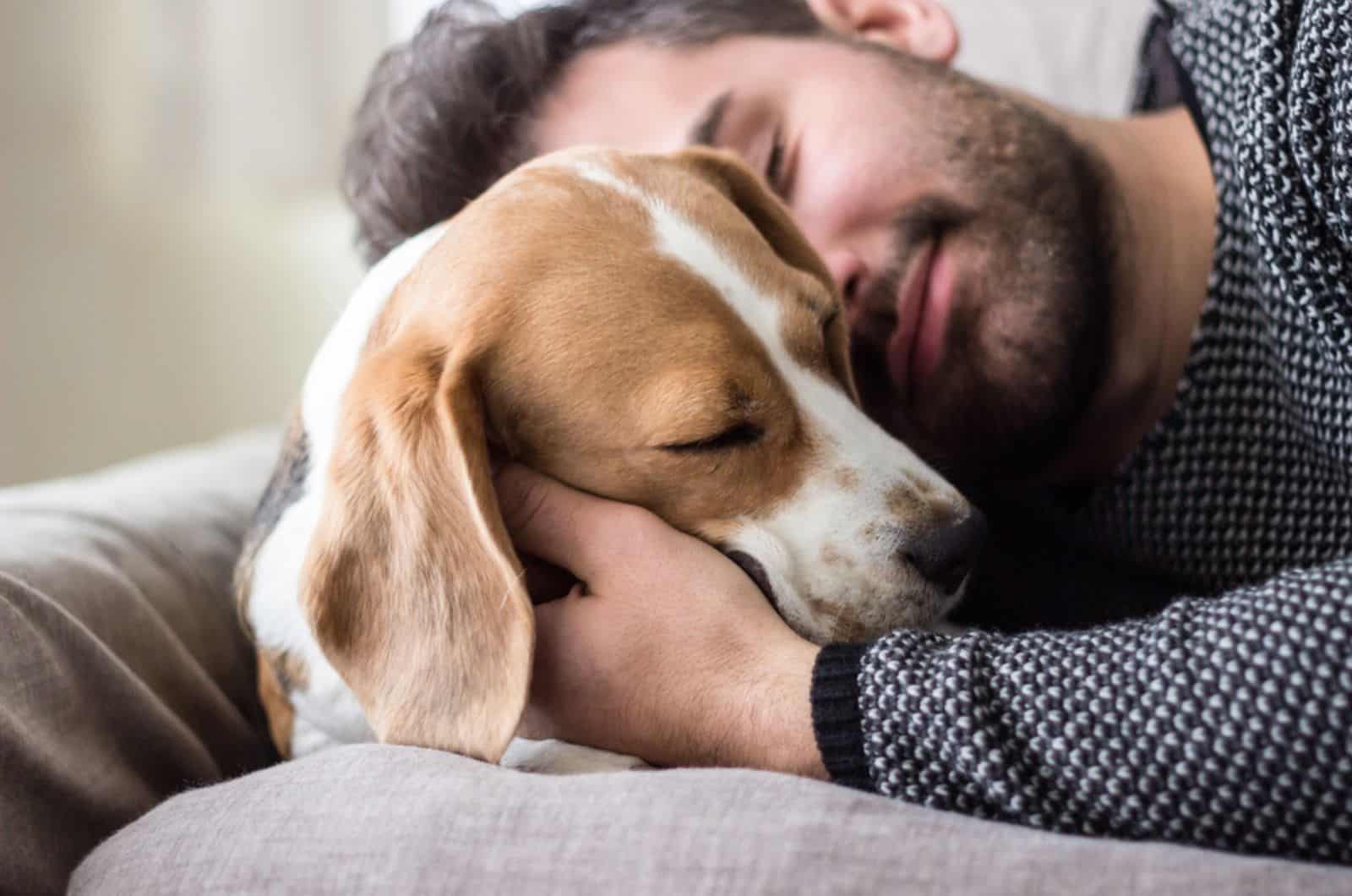 man cuddling with his dog on the couch