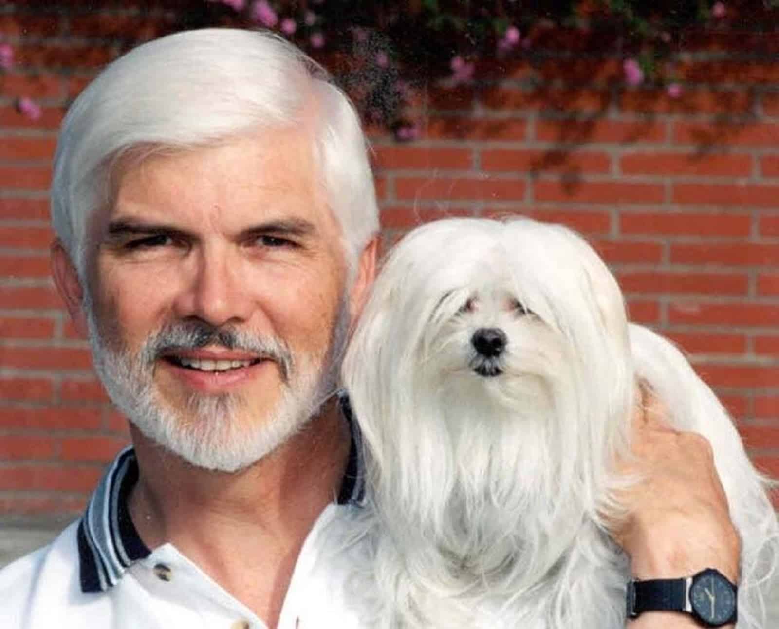 man with grey hair holding his dog on his shouder