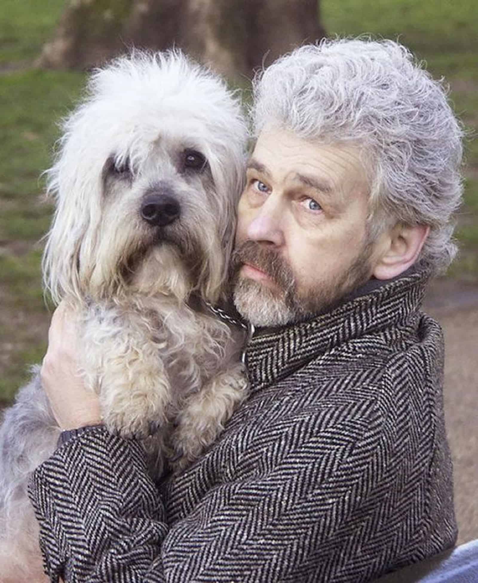 man with mustache holding his dog in arms