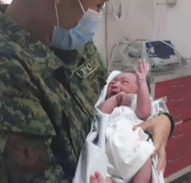 policeman holding the saved baby