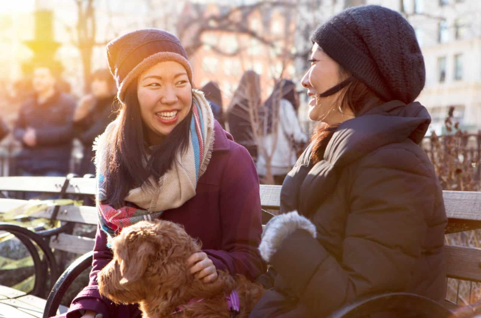 two women talking while sitting on the bench with dog