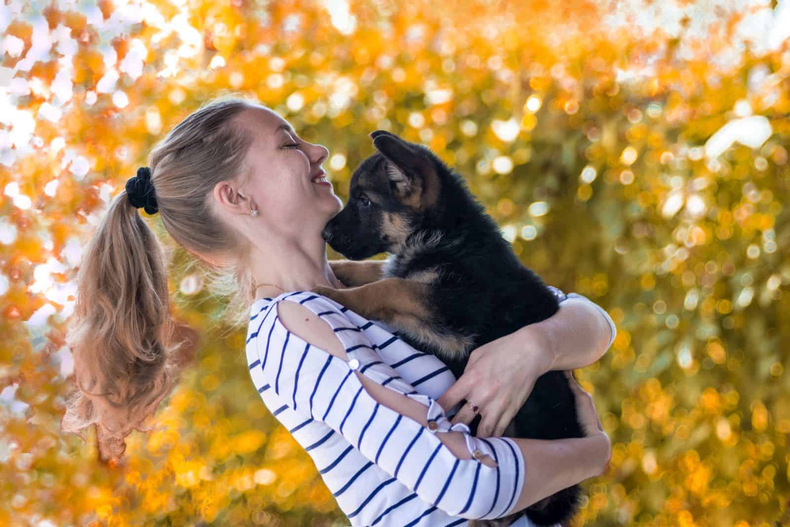 Happy girl holding a German shepherd puppy and smiling