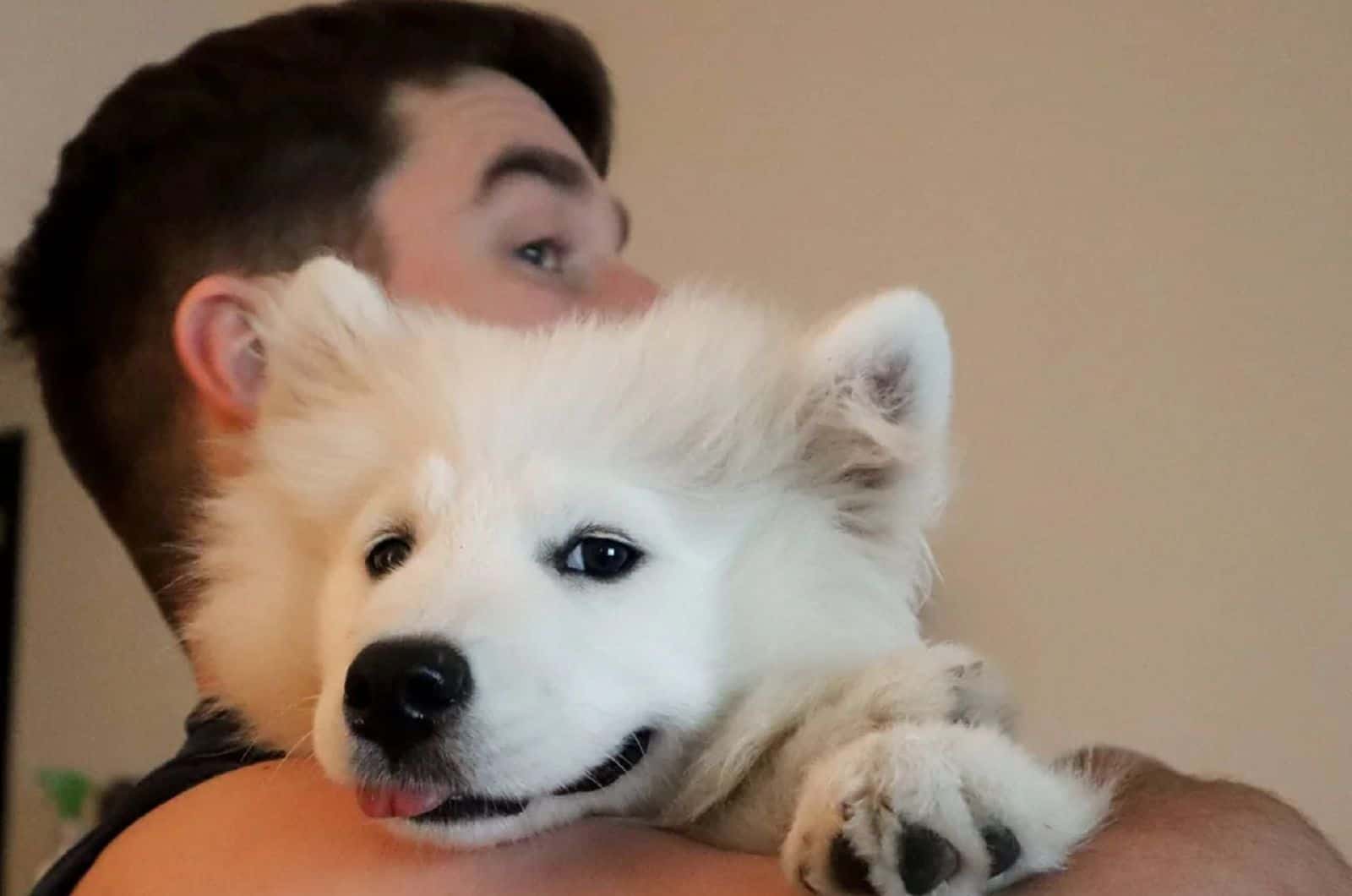 man holding his samoyed in arms
