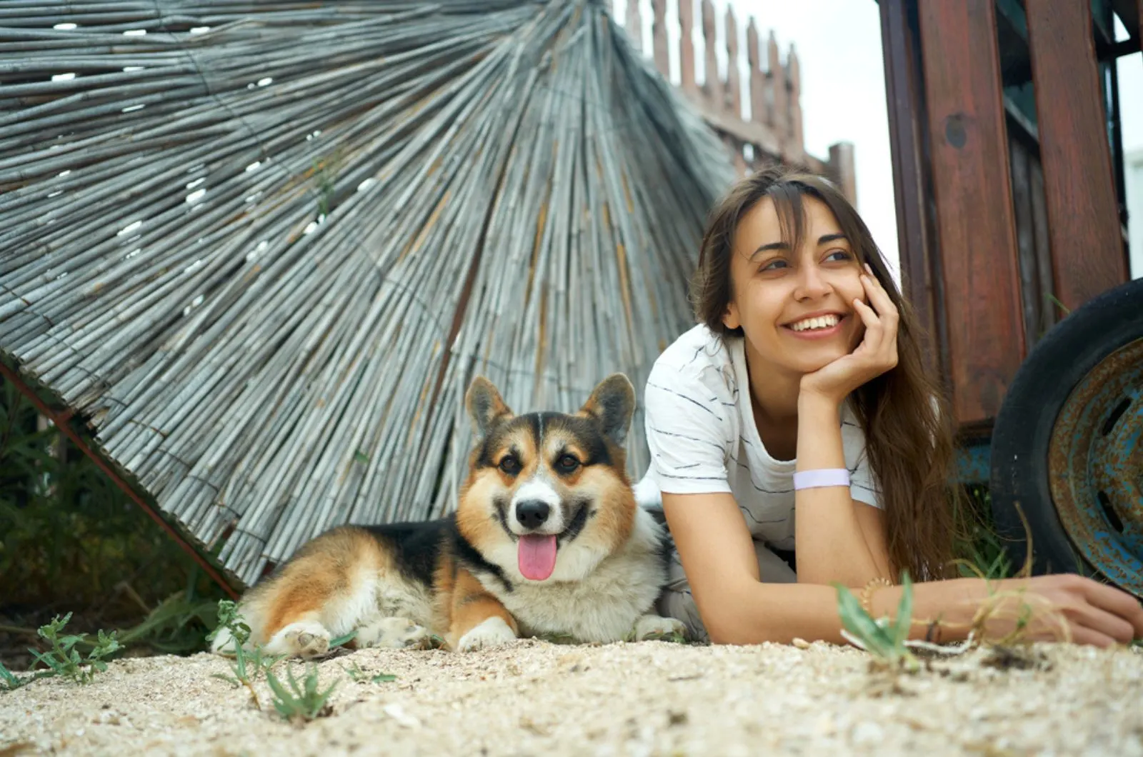 positive woman with her pet welsh corgi dog lying on the ground