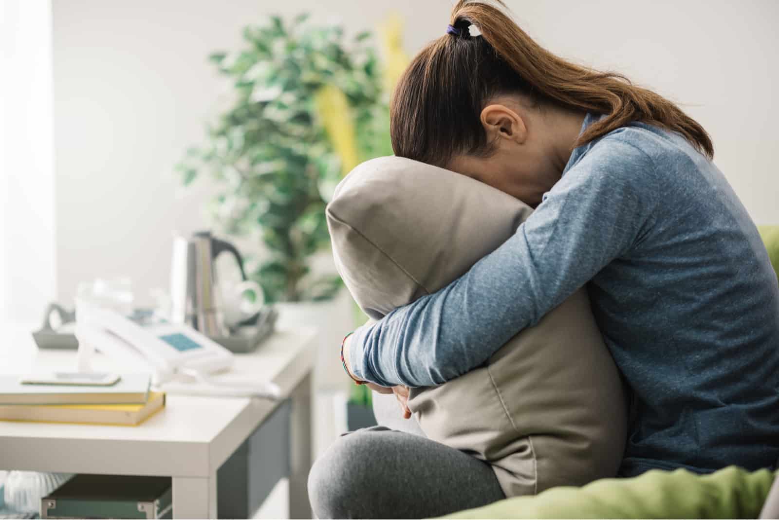 sad woman hugging pillow at home