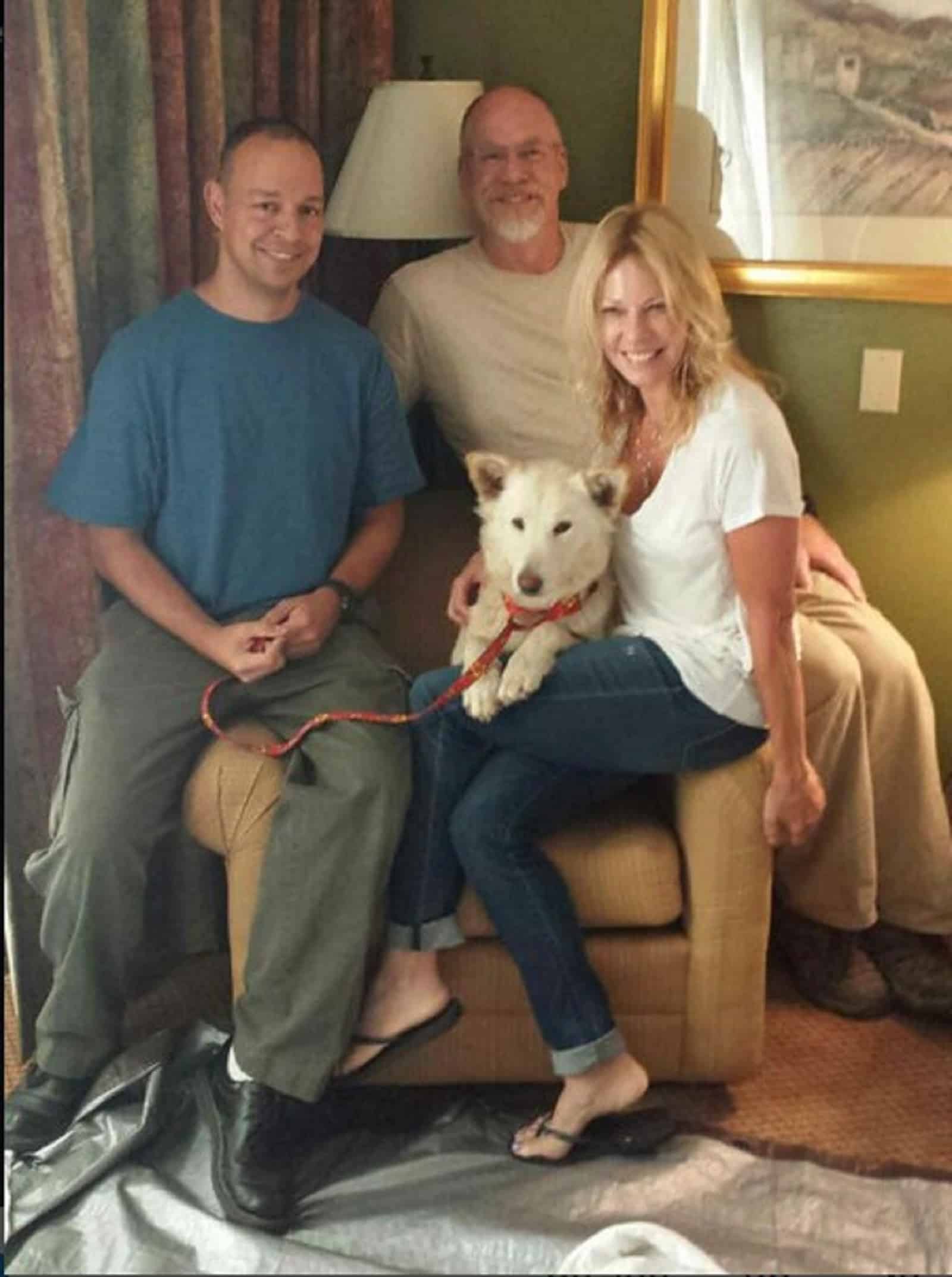 a group of people with white german shepherd dog sitting in the armchair