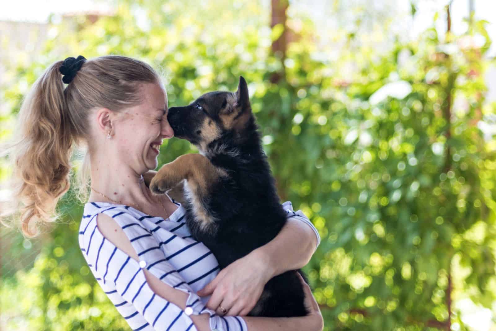 german shepherd puppy rub his face on a woman's face while she holding him