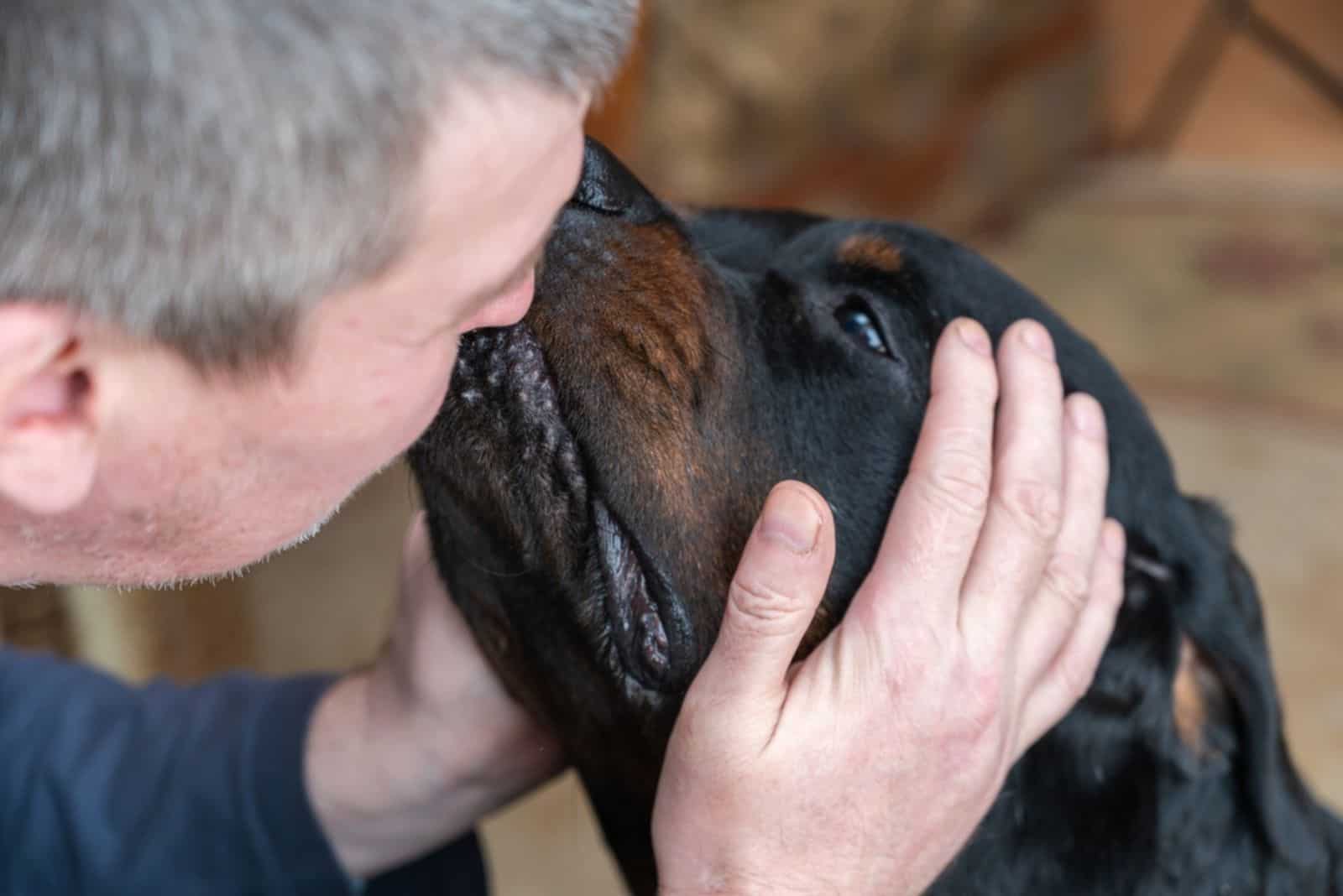 man cuddling his dog and kissing him