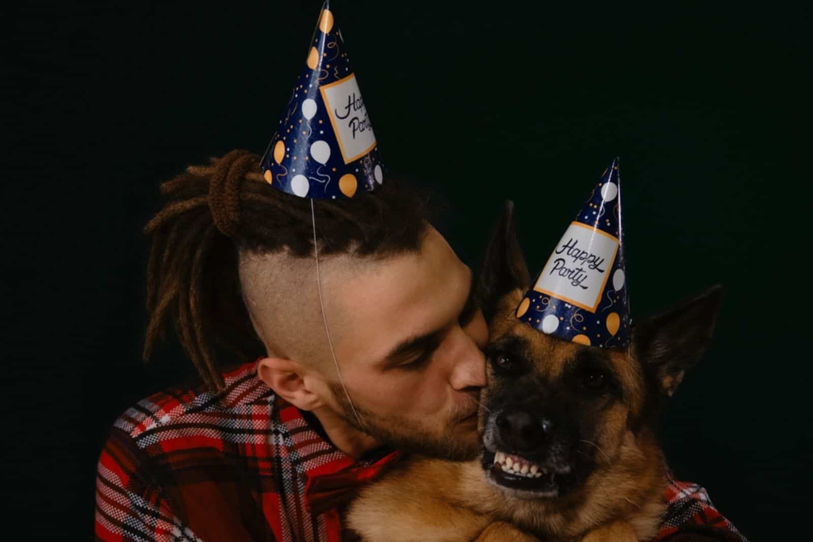 man kissing and hugging german shepherd dog while celebrating together some event