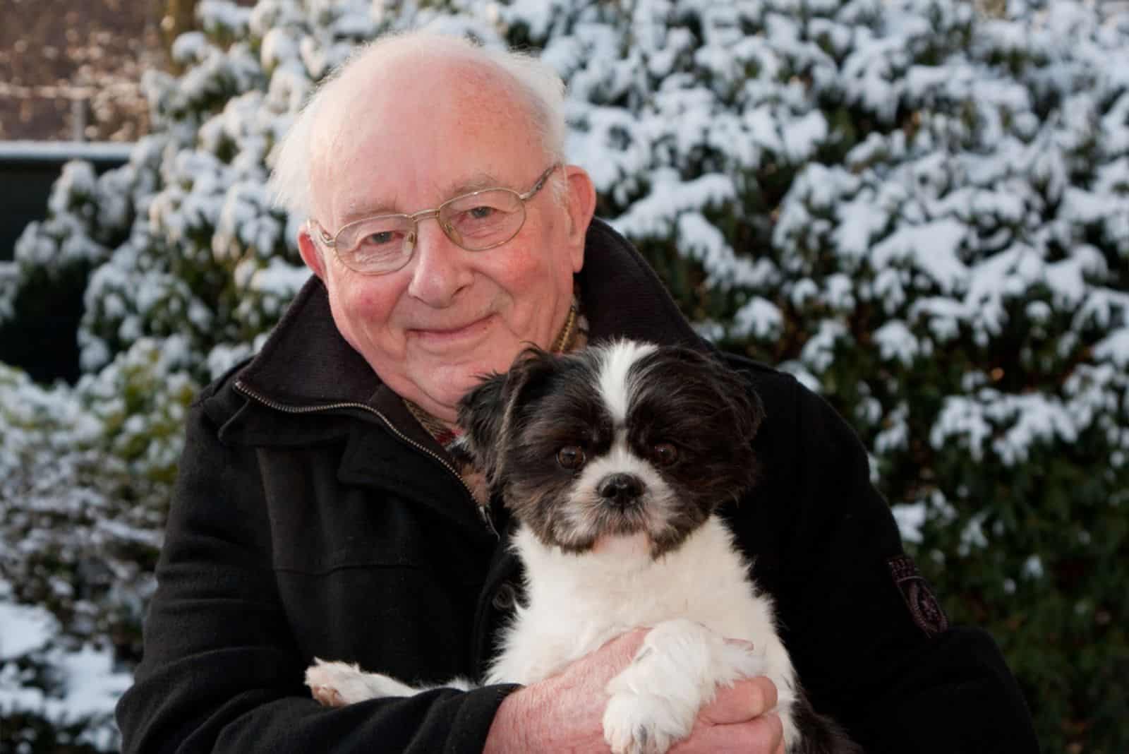 senior man with a shih tzu dog in his arms