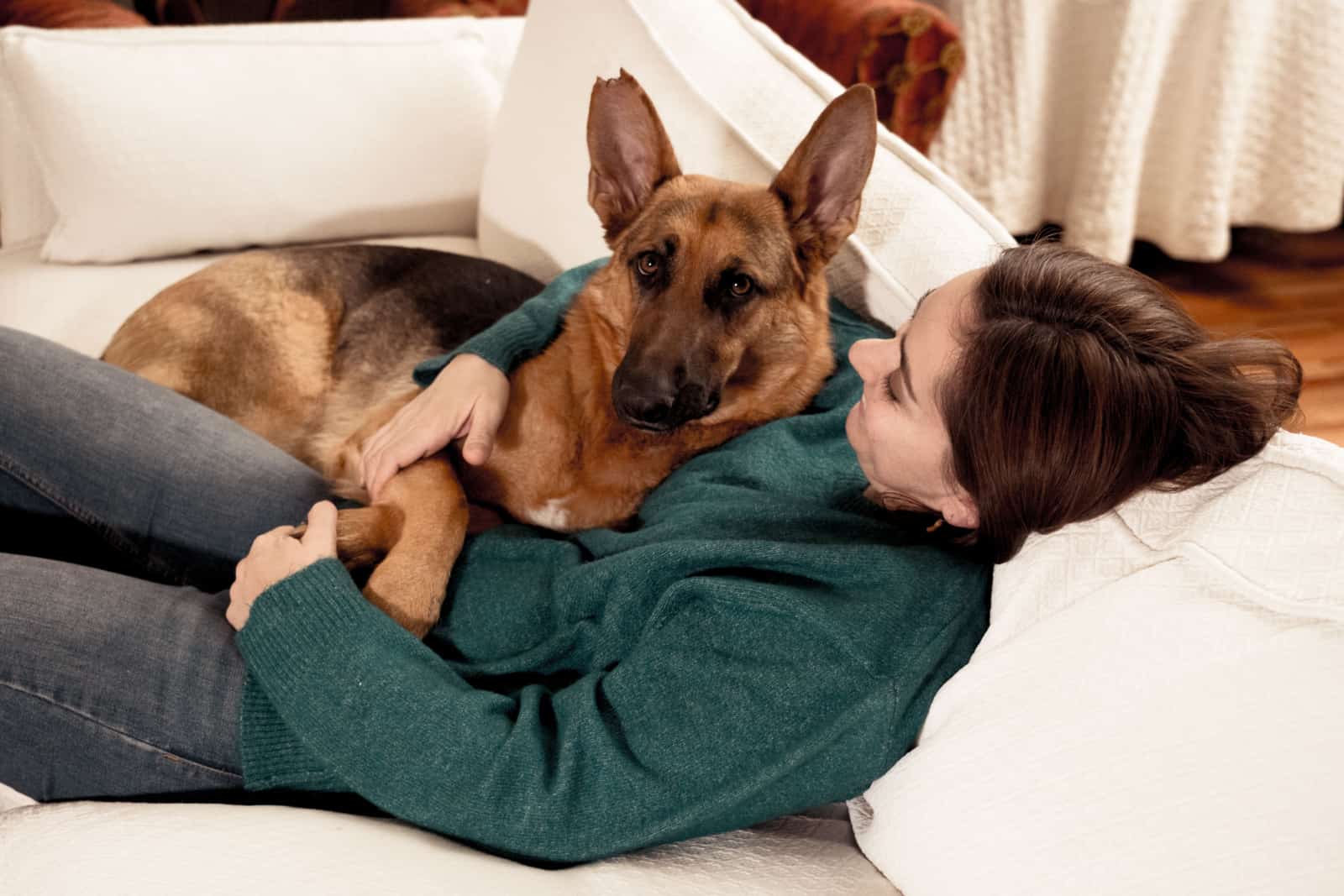 smiling woman hugging her dog german shepherd together in front of fireplace