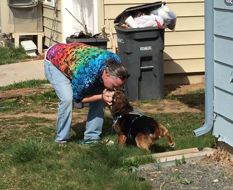 the owner kisses his dog in the garden